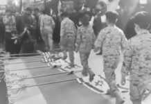 Jóvenes iraníes con uniformes militares caminan sobre banderas de EE.UU. e Israel